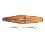 A set of three graduated scissors in leather case, the steel scissors stamped 'NCC Socy Ld.,