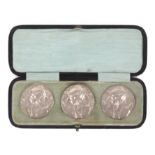 Buttons - a cased set of three large silver buttons each depicting a maiden's head amid foliage in
