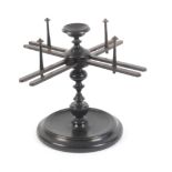 A 19th Century turned ebonised beech swift or wool winder, the turned base and pedestal supporting