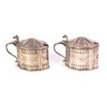 A pair of silver lidded mustard pots, of oval serpentine outline, pierced and engraved in the Adam
