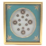 Buttons - a framed display of a set of fourteen early 19th Century enamel buttons, probably