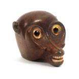 An early 19th Century carved wood snuff box in the form of an exaggerated monkey head, large glass