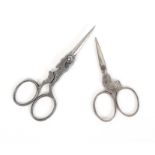 Two pairs of 19th Century polished steel figural scissors, comprising a pair with oval section
