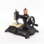 An early 20th Century sewing machine for a child, colour transfers on a black ground ‘Made in