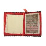 A needle book incorporating a miniature sampler dated 1828, the covers in red silk edged in black