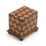 A documentary money box, decorated in cube pattern of rectangular form on a chamfered plinth base