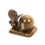 A gilt brass novelty tape measure in the form of a lion, its paws resting on a ball, emblematic of a