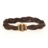 A 19th Century entwined and plaited hair mourning bangle, the floral engraved mount initialled to