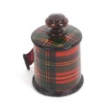 A Tartan ware cylinder tape measure (Stuart), the very slightly reduced printed tape wound from a