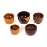 Five 19th Century knitting wool ball cups, four in lignum vitae, one in walnut, largest 8.5cms dia.