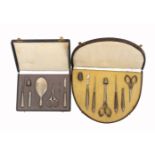Two early 20th Century continental leatherette cased sewing sets, the first of near semi-circular