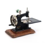 An early 20th Century sewing machine ‘Baby’, in gilt on black, wooden plinth base, additional