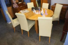 A pale oak oval extending dining table and six chairs