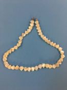 A mother of pearl necklace, each piece carved in the form of a fish