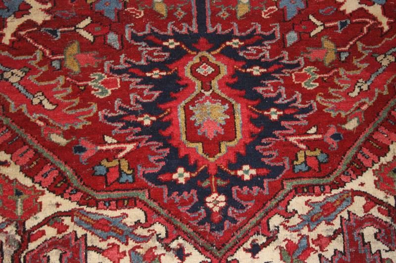A 1920's Heriz carpet, the madder red ground with central flower head medallion surrounded by