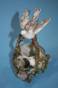 A Continental porcelain floral basket with a bird resting on the handle, 23cm height