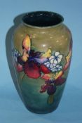 A tall Moorcroft vase, decorated with orchids on a graduating green ground, impressed marks. 26cm