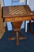 A Victorian walnut games/work table with chess board top, the top opening to reveal a green baize