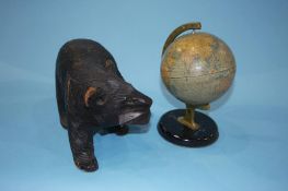 A carved Black Forest style bear and a small table globe