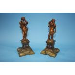 A pair of decorative brass cherubs on stands