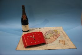 A red painted wall clock, an 'Everybody's War' map of South Africa and a bottle of champagne