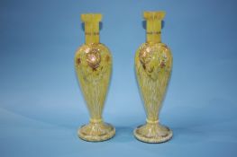 A pair of tall yellow glass vases, decorated with enamels