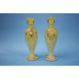 A pair of tall yellow glass vases, decorated with enamels