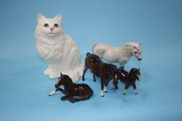 A seated Beswick cat and four Royal Doulton ponies