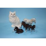 A seated Beswick cat and four Royal Doulton ponies