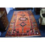 A Turkish design rug, the orange ground bearing a large triple medallion to centre, wide main border