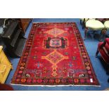 A Caucasian style rug, with triple central medallion on red ground and flower head border, 244cm x