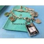 A Tiffany and Co 925 silver charm bracelet with five 925 charms and a stainless-steel padlock watch,