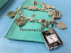 A Tiffany and Co 925 silver charm bracelet with five 925 charms and a stainless-steel padlock watch,