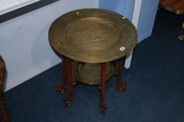An Oriental brass and carved fretwork, two tier folding table