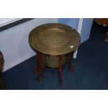 An Oriental brass and carved fretwork, two tier folding table