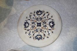 A white circular plate inlaid with mother of pearl coloured marble