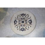 A white circular plate inlaid with mother of pearl coloured marble