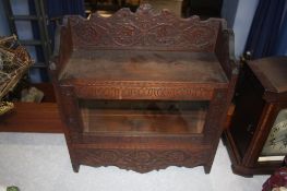 A carved wall cabinet with glazed door