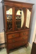 A Victorian walnut press with central oval bevelled glass door, flanked by two etched glass