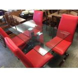 A modern glass top kitchen table, with chrome supports, with four red leather and chrome single