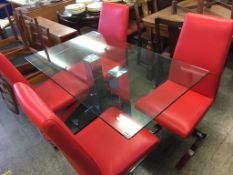 A modern glass top kitchen table, with chrome supports, with four red leather and chrome single