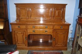 A large oak sideboard, with panelled and raised back, below a central recess, drawers and cupboard