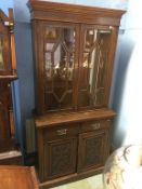 An Edwardian oak bookcase, with glazed doors, below two short drawers and two panelled doors