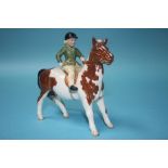 A Beswick model of a girl wearing a green jacket on a piebald pony