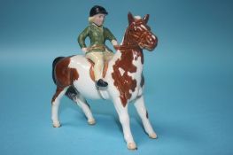 A Beswick model of a girl wearing a green jacket on a piebald pony