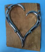 A wood mounted chrome heart shaped coat rack