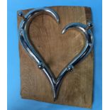 A wood mounted chrome heart shaped coat rack