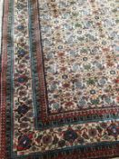 An Indian rug, the ivory ground with geometric flower heads, main border with tendrils and flower
