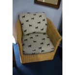A wicker work armchair, with dog patterned cushions