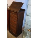 A 1930s oak tambour front cabinet, with reading stand